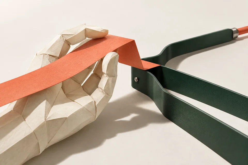 Paper-sculpted hand supporting a coral ribbon before a branching green guide.