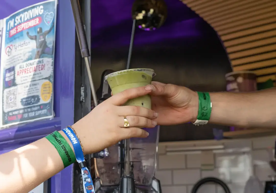 A matcha drink being handed to a customer at the horsebox