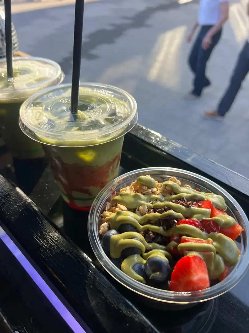 A fruit-topped bowl and matcha drinks at the serving hatch